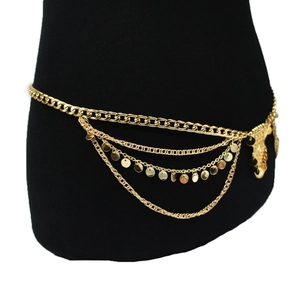 Detail of layered gold waist chain featuring sequins and vintage shield pendant charms