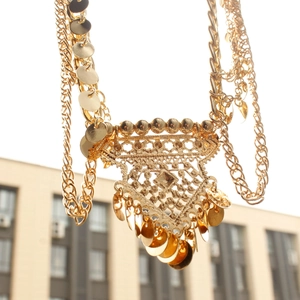 Macro view of bohemian gold layered chain necklace with triangle pendant and disk fringes