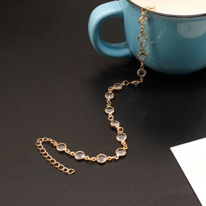 Detalle de tobillera chapada en oro con piedras de cristal redondas y cierre ajustable