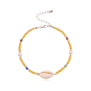 Detail eines gelben Perlen-Fußkettchens mit Evil-Eye-Charms und einer echten Muschel