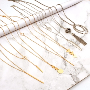 Conjunto de collares geométricos en oro y plata con borlas sobre soportes blancos