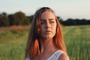 Detail of silver beaded hair chain with white pearls worn by a model in golden hour light