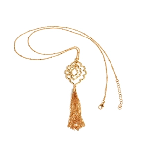Detalle de collar bohemio dorado con colgante floral de varias capas y borlas largas
