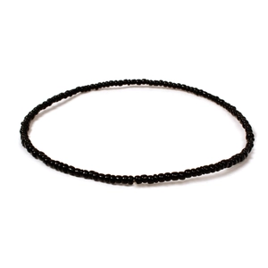Detailed view of handmade black beaded necklace with glossy finish on a white background