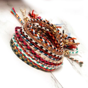 Detail of multi-colored braided friendship bracelets with small gold bead accents