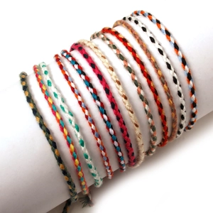 Detail of colorful hand-woven friendship bracelets on a white display holder