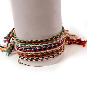 Macro shot of colorful handmade braided bracelets featuring gold beads and tassel details