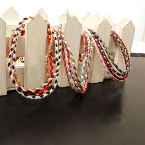 Detail of colorful hand-woven braided cords in ethnic style on a white wooden fence display
