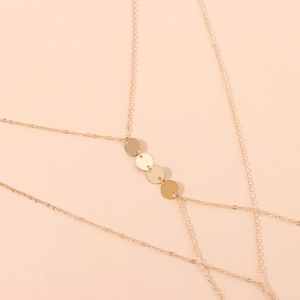 Detail shot of golden sequin pendants and delicate body chain with high metallic luster