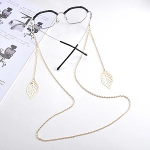 Detail shot of a golden metal eyeglass chain featuring delicate leaf pendants