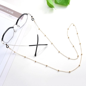 Detalle de cadena de cuentas de metal dorado con lazos antideslizantes para gafas