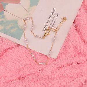 Elegantes goldenes Perlen-Fußkettchen mit kleinen weißen Perlen auf rosa Samtstoff