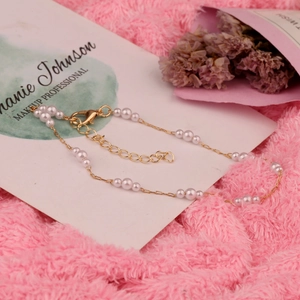 Elegantes goldenes Perlen-Fußkettchen mit weißen Perlen auf weichem rosa Plüschhintergrund