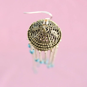 Macro view of vintage bronze hollow earring with light blue beaded tassels