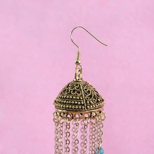 Detailed close-up of vintage gold Jhumka earrings with turquoise beads and long tassels