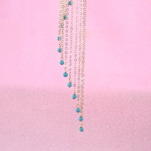 Detailed macro view of bohemian golden fringe chains with turquoise beads embellishments