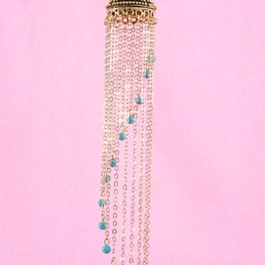 Macro detail of bohemian alloy tassel earrings featuring gold chains and turquoise beads