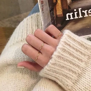 Close-up of minimalist gold thin bands worn by model against a soft knit background