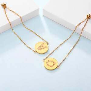 Detailed macro view of adjustable gold bracelets with zircon letter pendants A and G