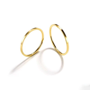 Macro detail of two stackable polished gold stainless steel thin rings on white surface
