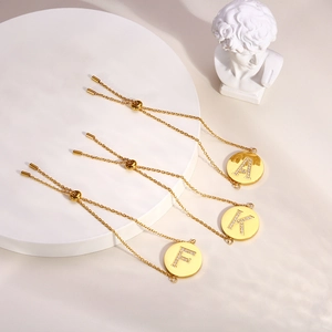 Detailed slider closure on three gold bracelets featuring Zircon initial pendants A, K and F
