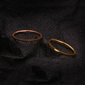 Minimalist stainless steel ring set in gold and rose gold finish on a black stone surface