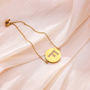 Detail of adjustable gold stainless steel bracelet featuring zircon paved letter F pendant