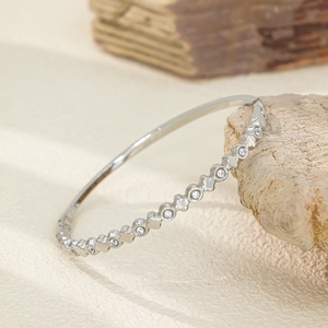 Détail du bracelet trèfle argenté avec pierres de zircon sur support en pierre