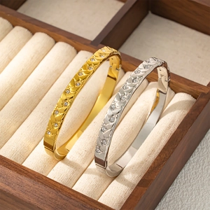 Vista detallada de brazaletes de oro y plata con circonitas en un joyero elegante
