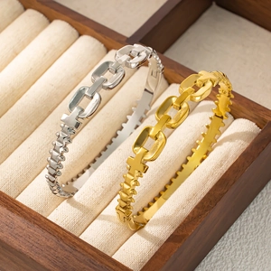 Détail de bracelets à maillons dorés et argentés présentés dans une boîte à bijoux en bois