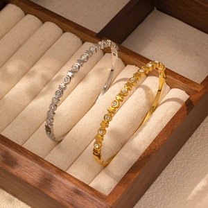 Detalle de brazaletes chapados en oro de 18K y plata con estrellas de circonita y cierre