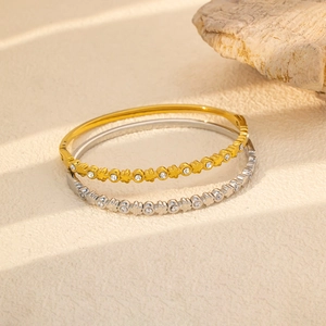 Detalle de brazaletes de oro y plata con patrones de trébol huecos y piedras de circón