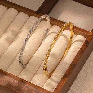 Detalle de brazaletes ondulados en oro y plata con piedras de circonita pavé