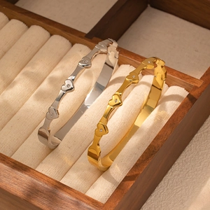 Close-up of gold and silver heart-shaped titanium steel bracelets with zircon stones