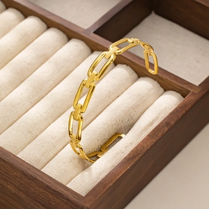 Dettaglio di un bracciale rigido a catena dorata lucida su una scatola di gioielli in velluto