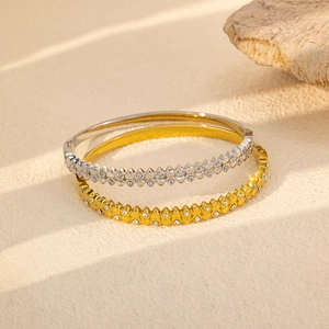 Dettaglio di bracciali in acciaio al titanio oro e argento con motivi a cuore e zirconi