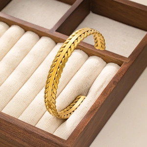 Bracciale rigido aperto in acciaio inossidabile dorato con trama intrecciata su supporto