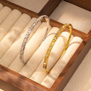Primer plano detallado de brazaletes de oro y plata con circonitas en un joyero elegante