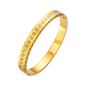 Détail du bracelet doré avec motifs de cœurs embossés et strass brillants à charnière