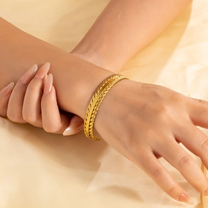 Dettaglio macro del bracciale rigido a C in acciaio dorato 18k con trama intrecciata