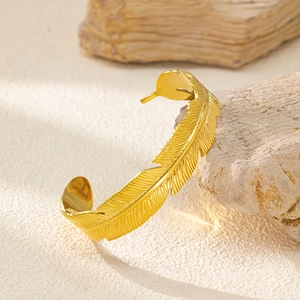 Dettaglio del bracciale aperto a piuma dorata con trame sottili su pietra naturale