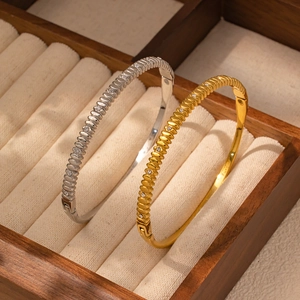 Dettaglio macro di bracciali in acciaio al titanio oro e argento con zirconi incastonati