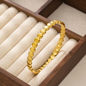 Detailed view of a gold beaded bangle with round spheres placed in a luxury wooden gift box
