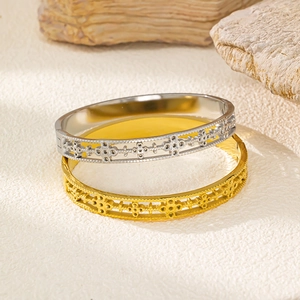 Dettaglio del motivo a trifoglio traforato su bracciali in acciaio inox oro e argento