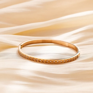 Detailed view of gold plated bangle with diamond pattern and sparkling zircon stones