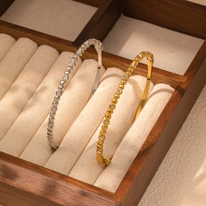 Detalle de brazaletes de cuentas doradas y plateadas con estrellas de circón en joyero