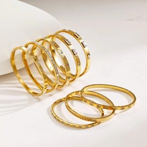 Elegant gold stainless steel bangle set with zircon accents on minimalist white display