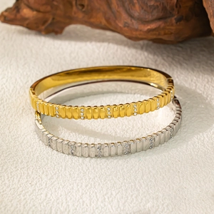 Diamantbesetzte Armreifen aus Titanstahl in Gold und Silber mit vertikaler Streifenstruktur