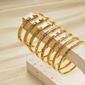 Group of golden stainless steel bangles with zircon accents on stone blocks display