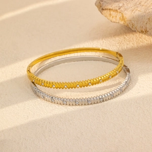 Detail of twisted cable gold and silver bangles with inlaid cubic zirconia and side hinge